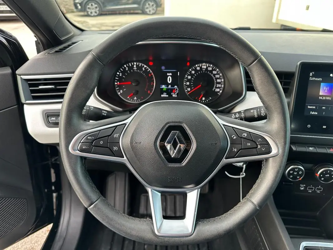 Vue intérieure centrée sur le volant noir de la Renault Clio V avec tableau de bord et écran tactile visibles.