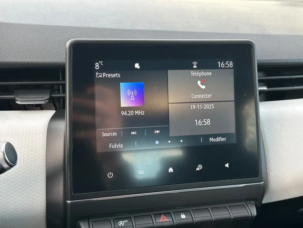 Écran tactile central de la Renault Clio V noire, affichant la radio FM et les options téléphone à 16h58.