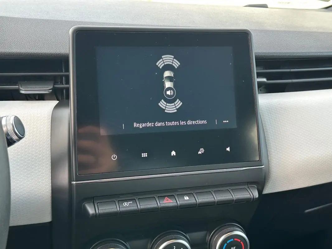 Écran tactile central affichant l'aide au stationnement dans l'habitacle clair d'une Renault Clio V noire.