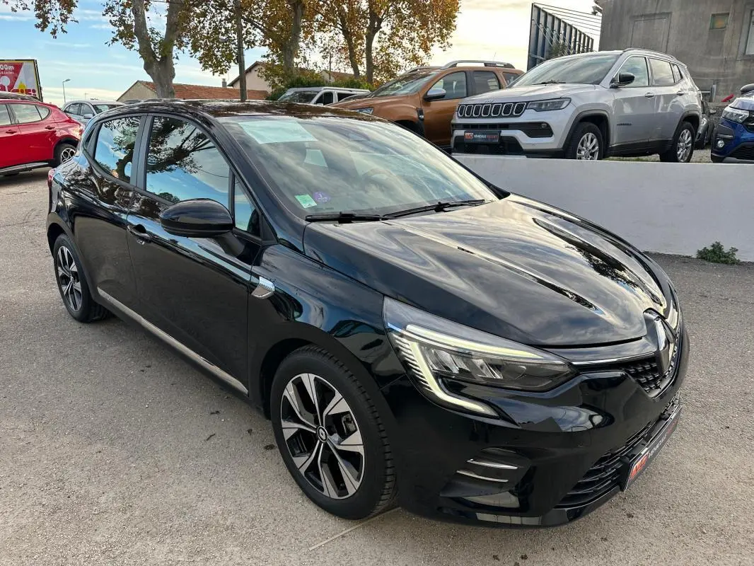 Renault Clio V SCe 65 noir en 3/4 avant droit, avec jantes alliage 16 pouces et feux LED allumés.