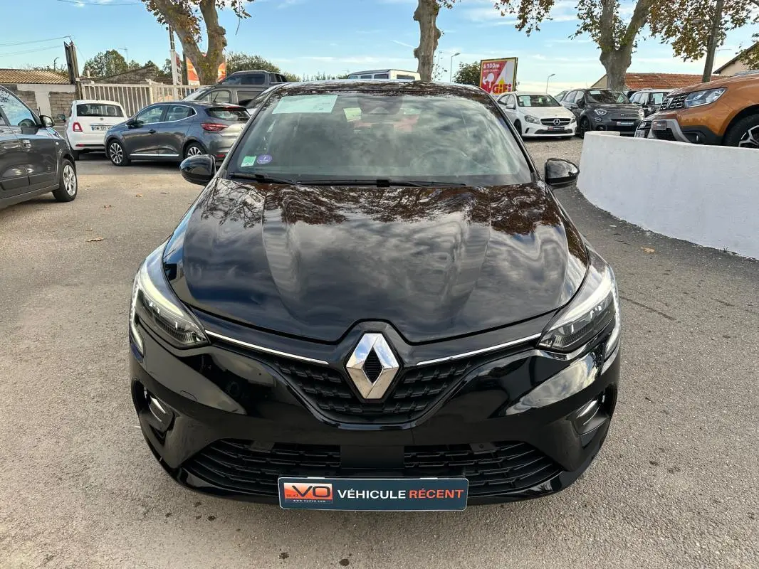 Vue frontale d'une Renault Clio V SCe 65 Limited noire, avec phares allumés et calandre chromée visible.
