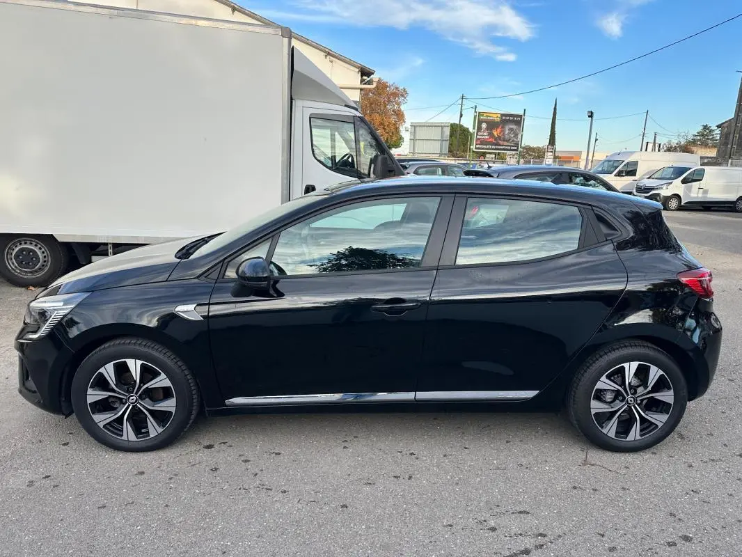 Profil côté gauche d'une Renault Clio V noire avec jantes alliage 16 pouces, stationnée en extérieur par temps clair.
