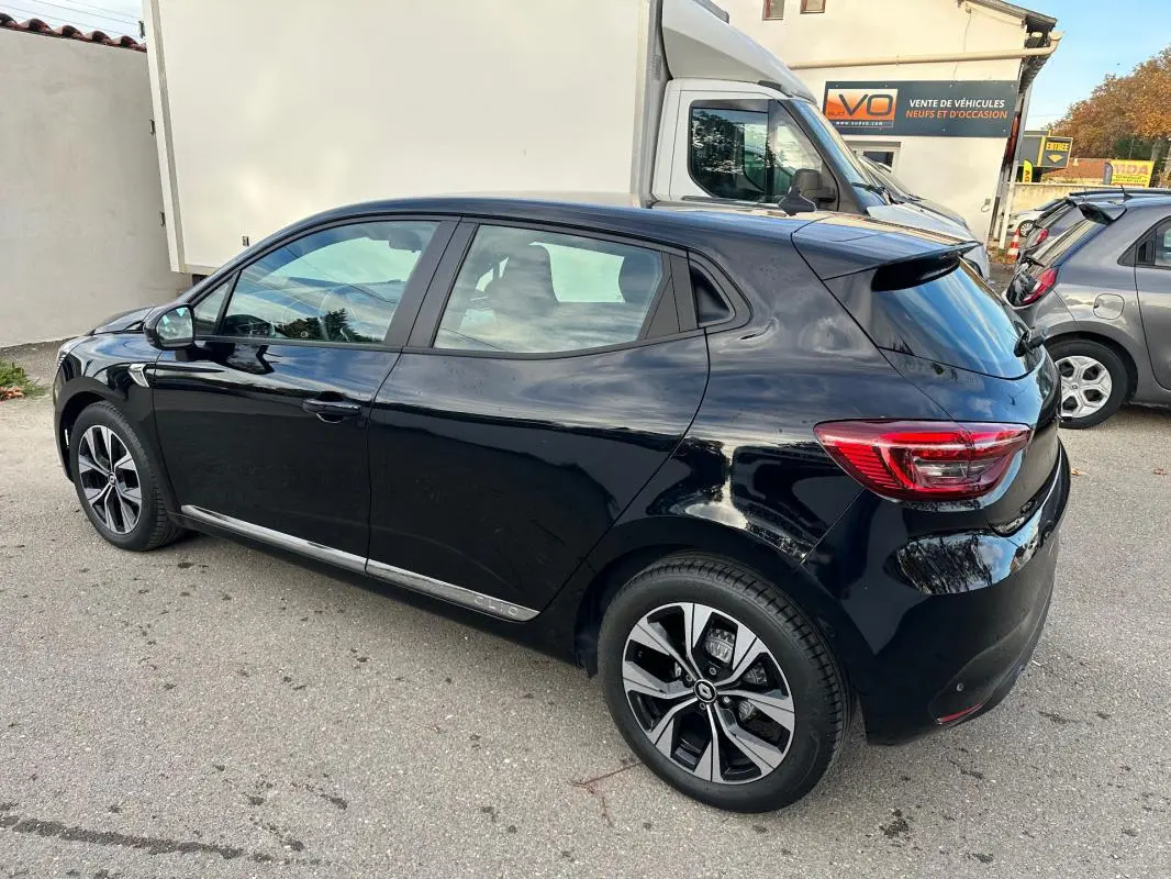 Vue 3/4 arrière droite d'une Renault Clio V SCe 65 noire avec jantes alliage 16 pouces stationnée en extérieur.