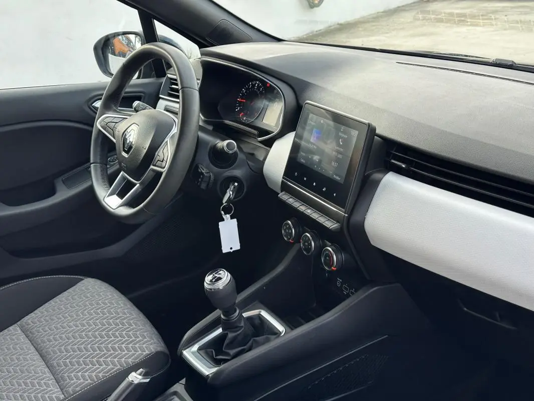 Vue intérieure côté conducteur de la Renault Clio V SCe 65 21 Limited avec volant, écran tactile et levier de vitesse manuel.