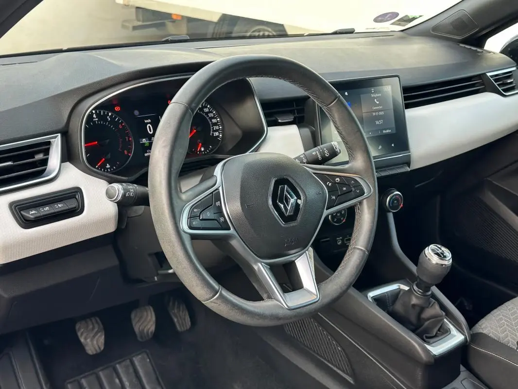 Vue intérieure côté conducteur de la Renault Clio V SCe 65 21 Limited avec volant cuir, tableau de bord digital et levier de vitesse manuel.