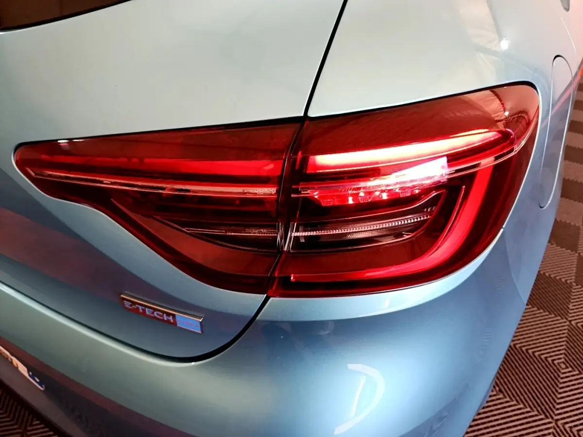 Gros plan sur le feu arrière droit rouge d’une Renault Clio Business E-Tech hybride bleu clair, avec logo E-Tech visible.