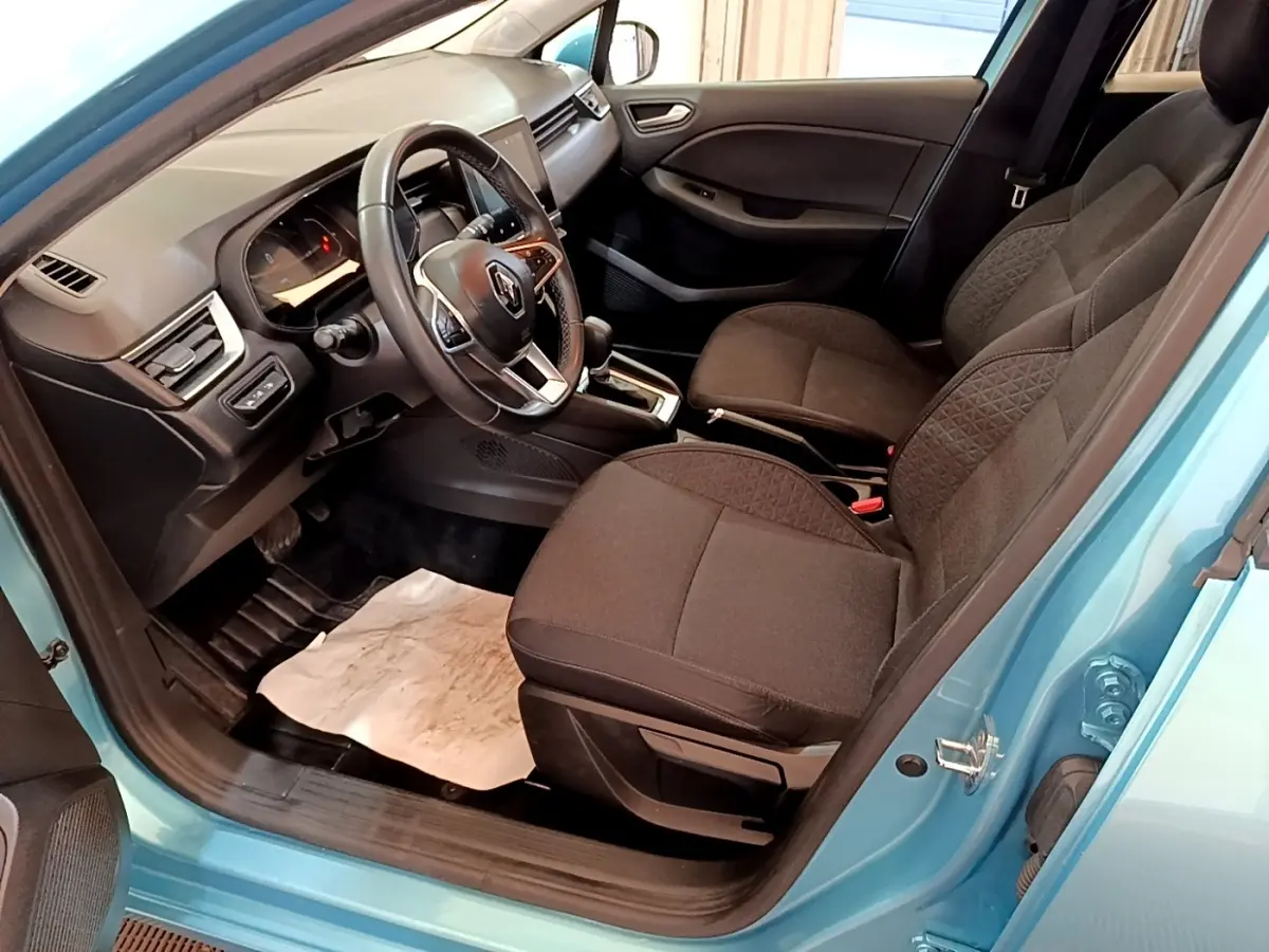 Vue intérieure côté conducteur de la Renault Clio Business E-Tech hybride bleu, avec sièges noirs et volant multifonctions.