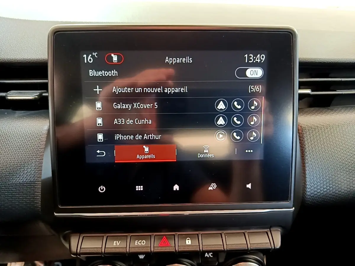 Écran tactile central affichant la connexion Bluetooth dans l’habitacle de la Renault Clio Business E-Tech hybride bleu, vue de face.