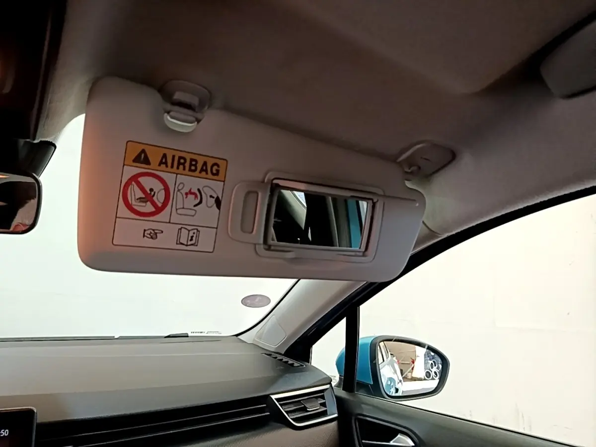 Vue intérieure côté passager de la Renault Clio Business E-Tech hybride bleu, avec pare-soleil ouvert et rétroviseur latéral visible.