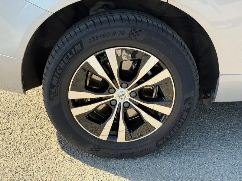 Gros plan sur la roue avant droite du Volvo XC60 gris, jante alliage bicolore et pneu Michelin Pilot Sport.