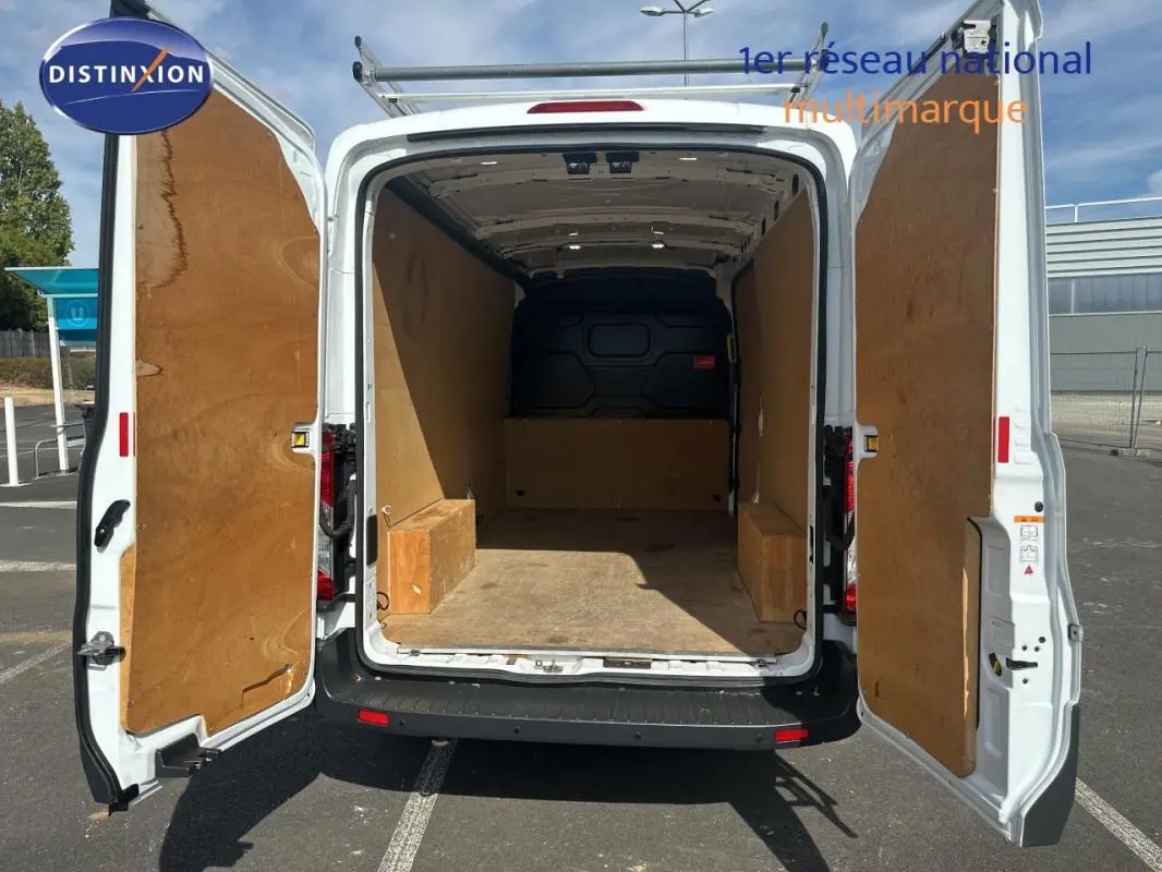 Vue arrière du Ford Transit Fourgon blanc 2015 avec portes ouvertes montrant l’espace de chargement vide et doublure boisée.