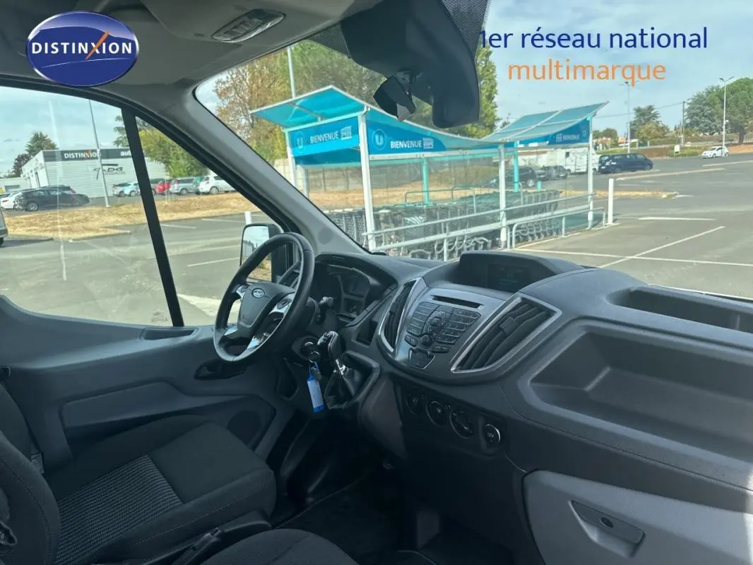 Vue intérieure côté conducteur du Ford Transit Fourgon blanc, montrant le tableau de bord et le volant.