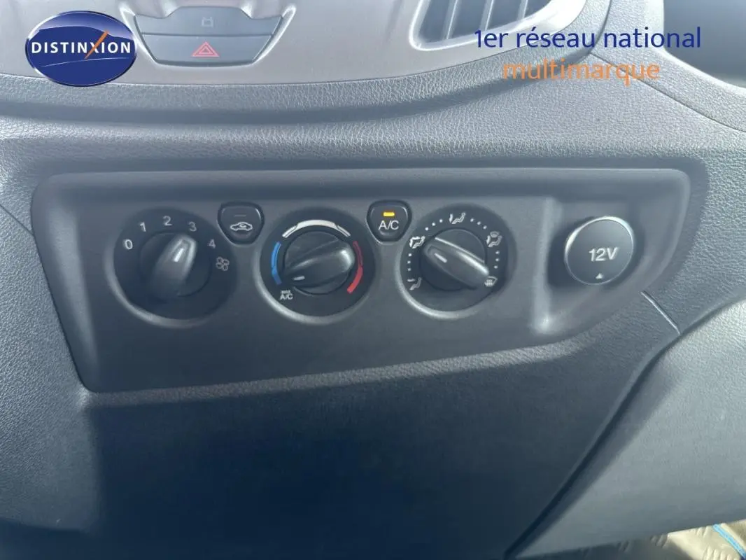 Tableau de bord du Ford Transit Fourgon blanc 2015, vue rapprochée des commandes de climatisation et prise 12V.