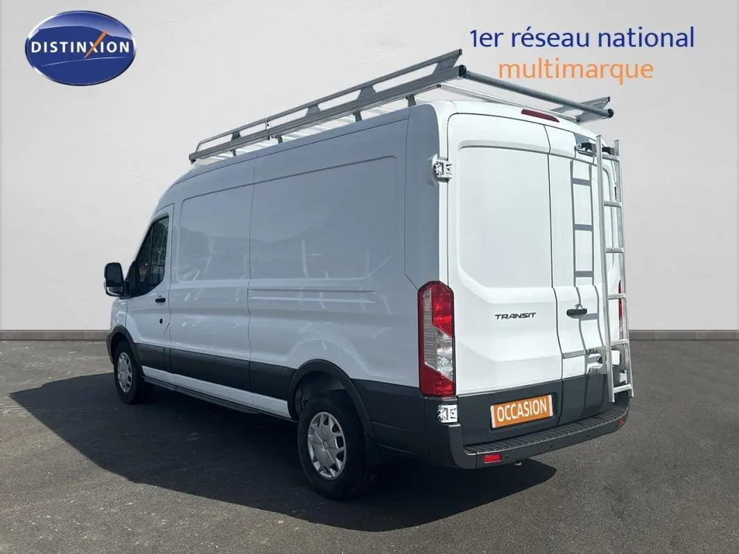 Vue 3/4 arrière droite d’un Ford Transit Fourgon blanc avec galerie et échelle sur porte arrière.