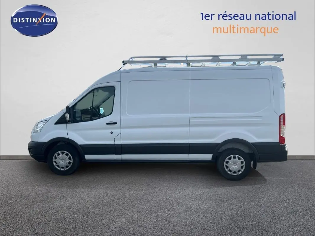 Vue latérale gauche d'un fourgon Ford Transit blanc avec galerie de toit et jantes classiques 16 pouces.