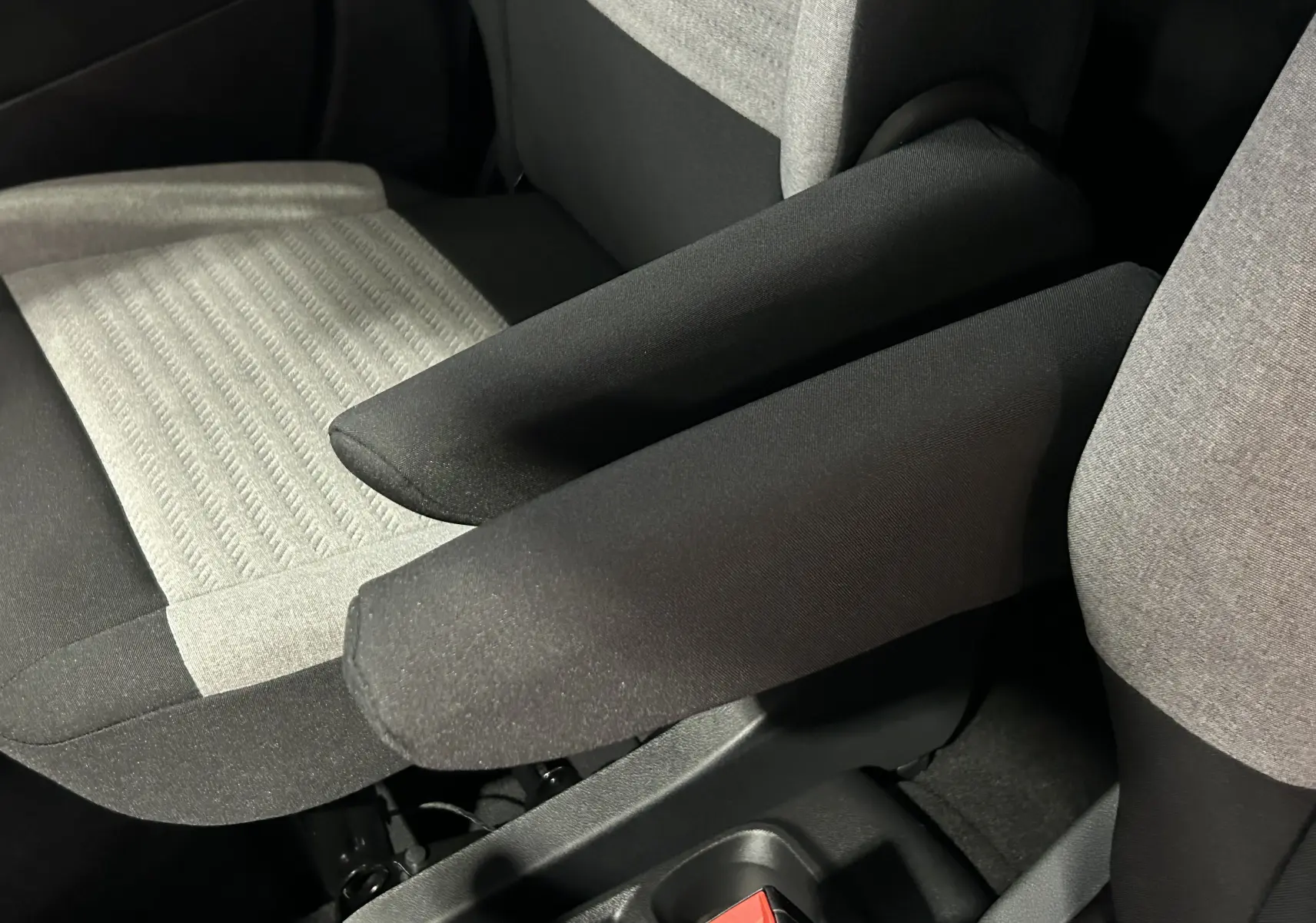 Détail des accoudoirs noirs et tissu gris clair des sièges avant du Citroën Berlingo Multispace 2025.