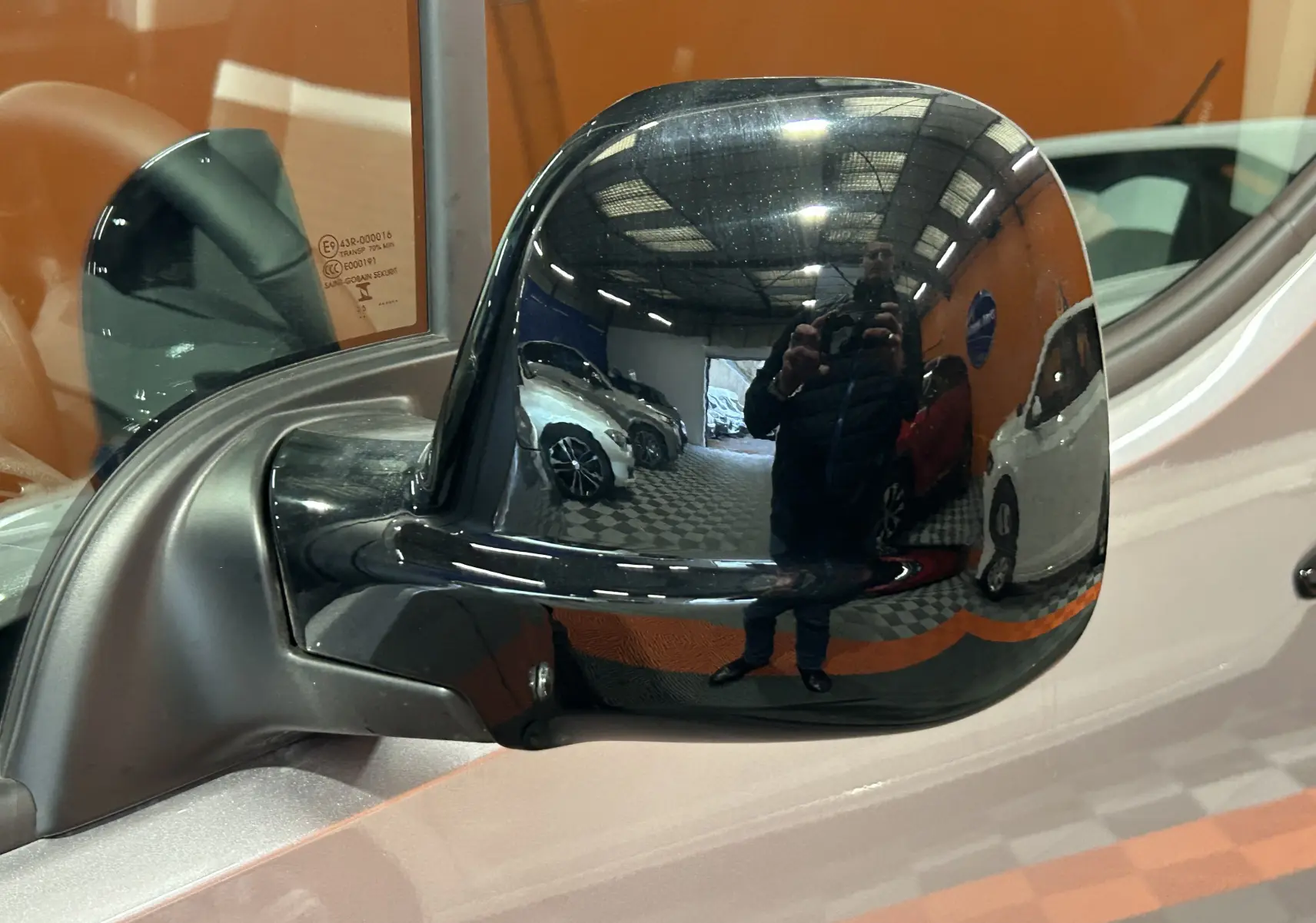 Rétroviseur noir côté gauche du Citroën Berlingo Multispace gris Artense, reflet d'un garage intérieur avec plusieurs véhicules.