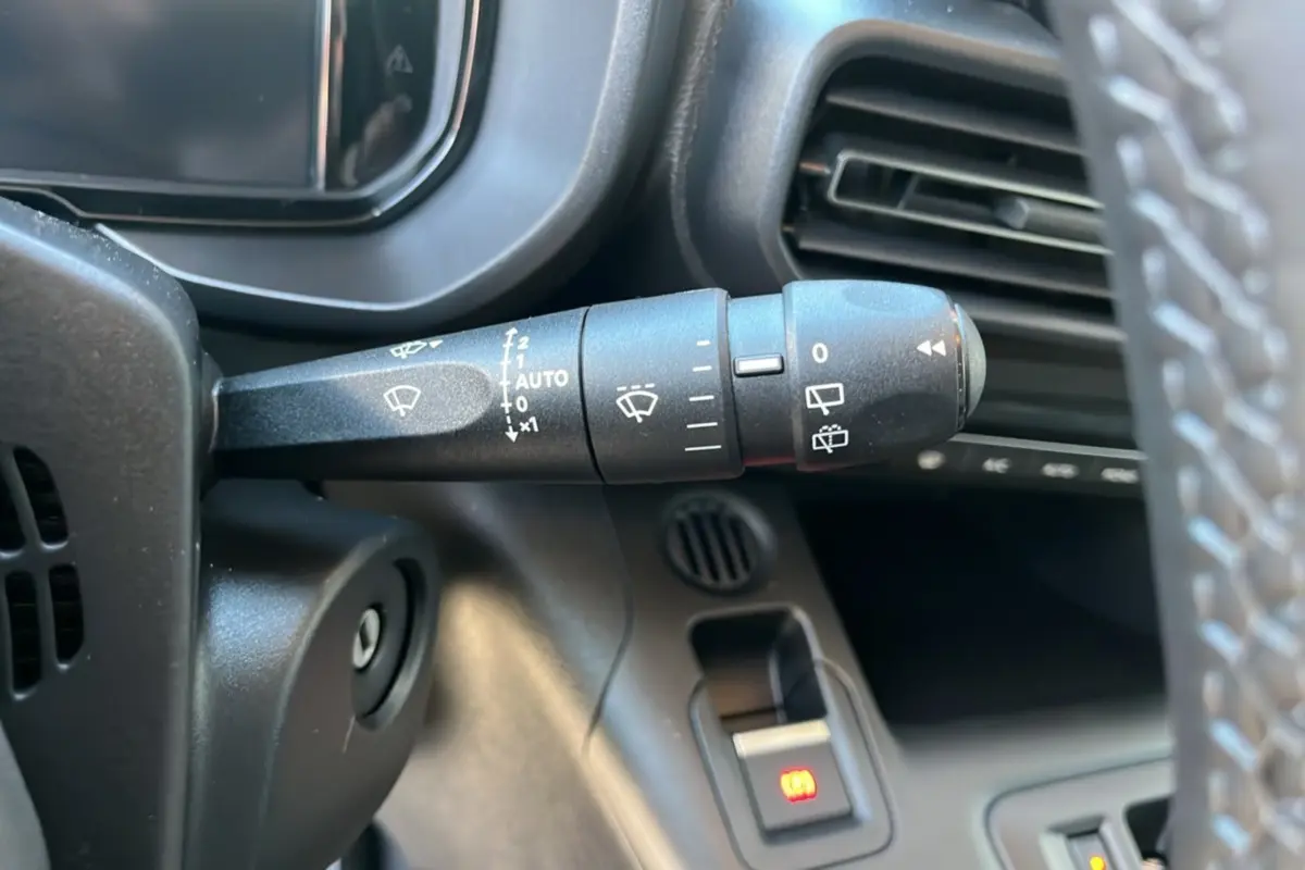 Gros plan sur la commande des essuie-glaces à gauche du volant dans l’habitacle du Citroën Berlingo noir perla nera 2026.