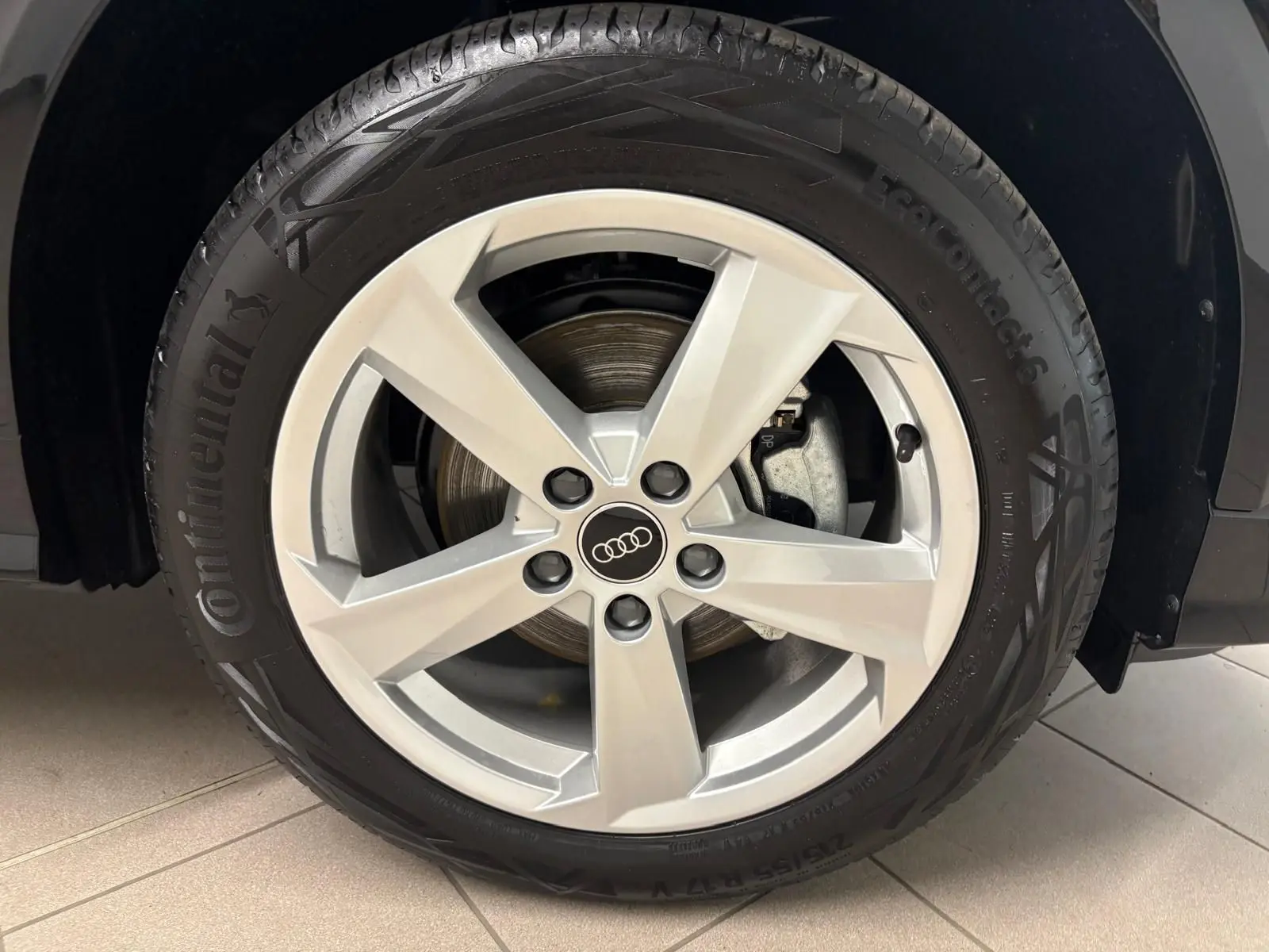 Gros plan sur la roue avant droite d’un Audi Q2 Noir Mythic avec jante argentée à cinq branches.