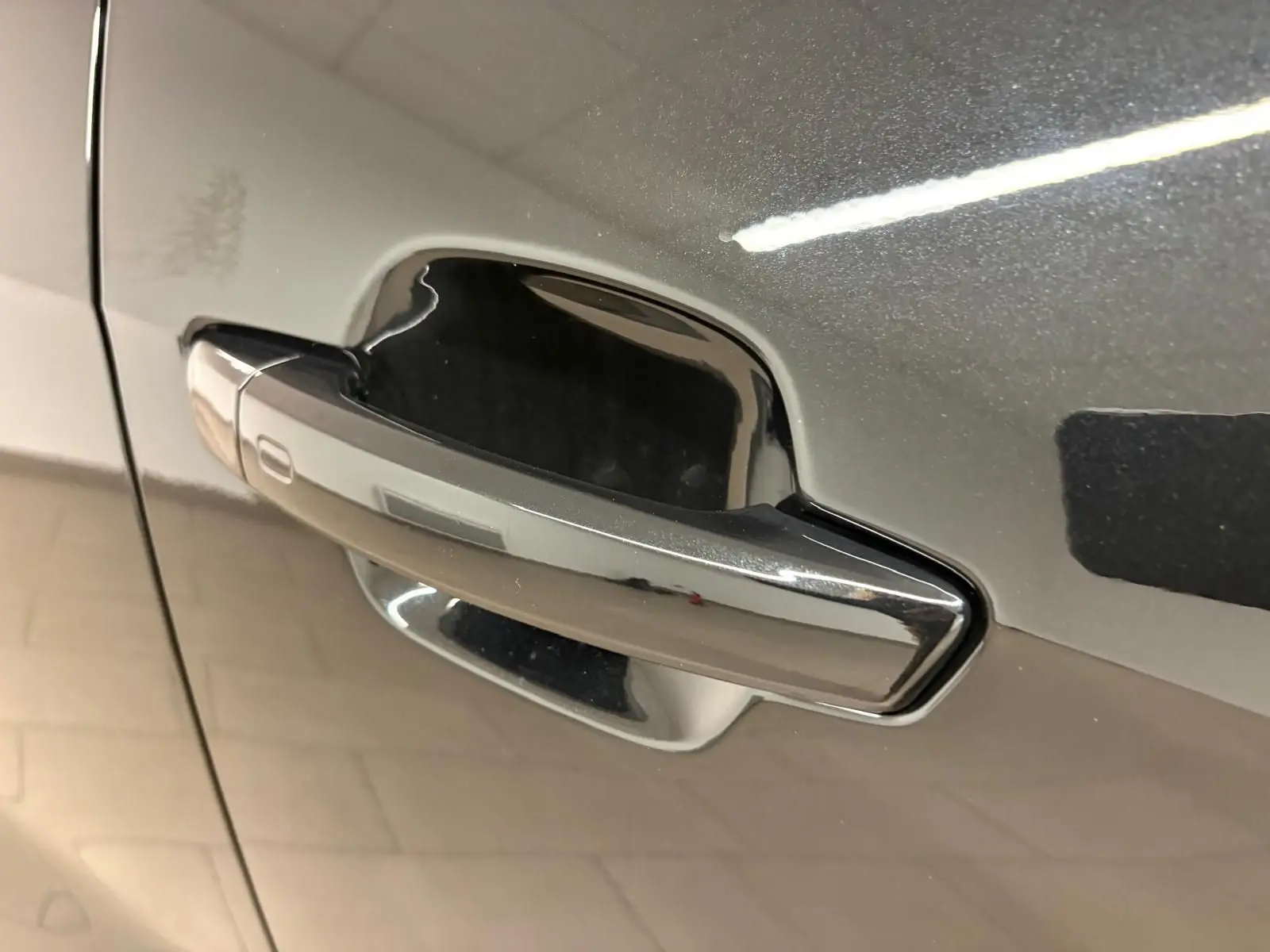 Poignée de porte chromée sur la portière avant gauche d’un Audi Q2 Noir Mythic 2026, finition S Line.