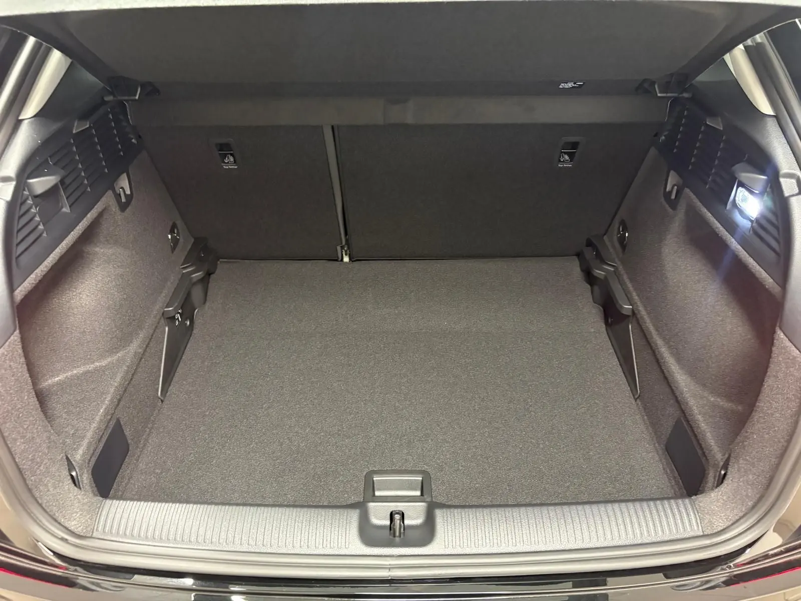 Coffre ouvert vu de l'arrière d'un Audi Q2 35 TFSI S Line noir Mythic, montrant un espace de chargement propre et éclairé.