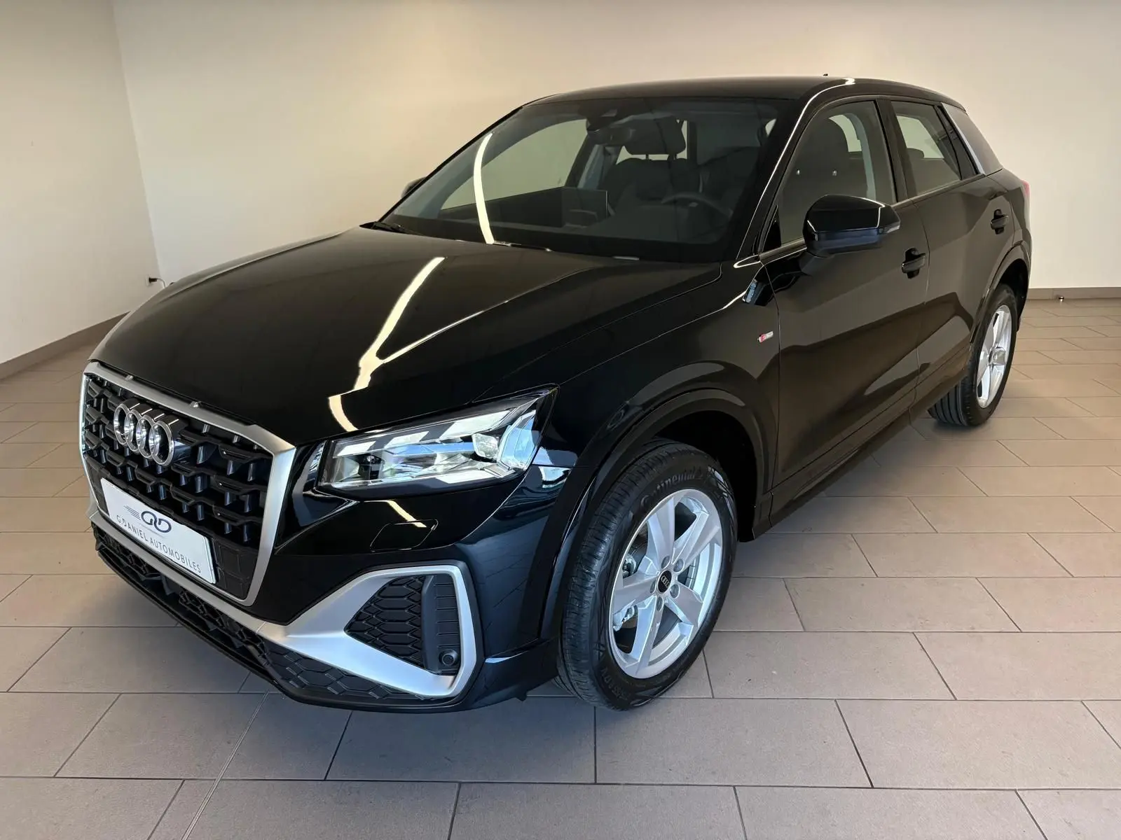 Audi Q2 35 TFSI S Line noir mythic, vue 3/4 avant droit, avec calandre hexagonale et jantes argentées.