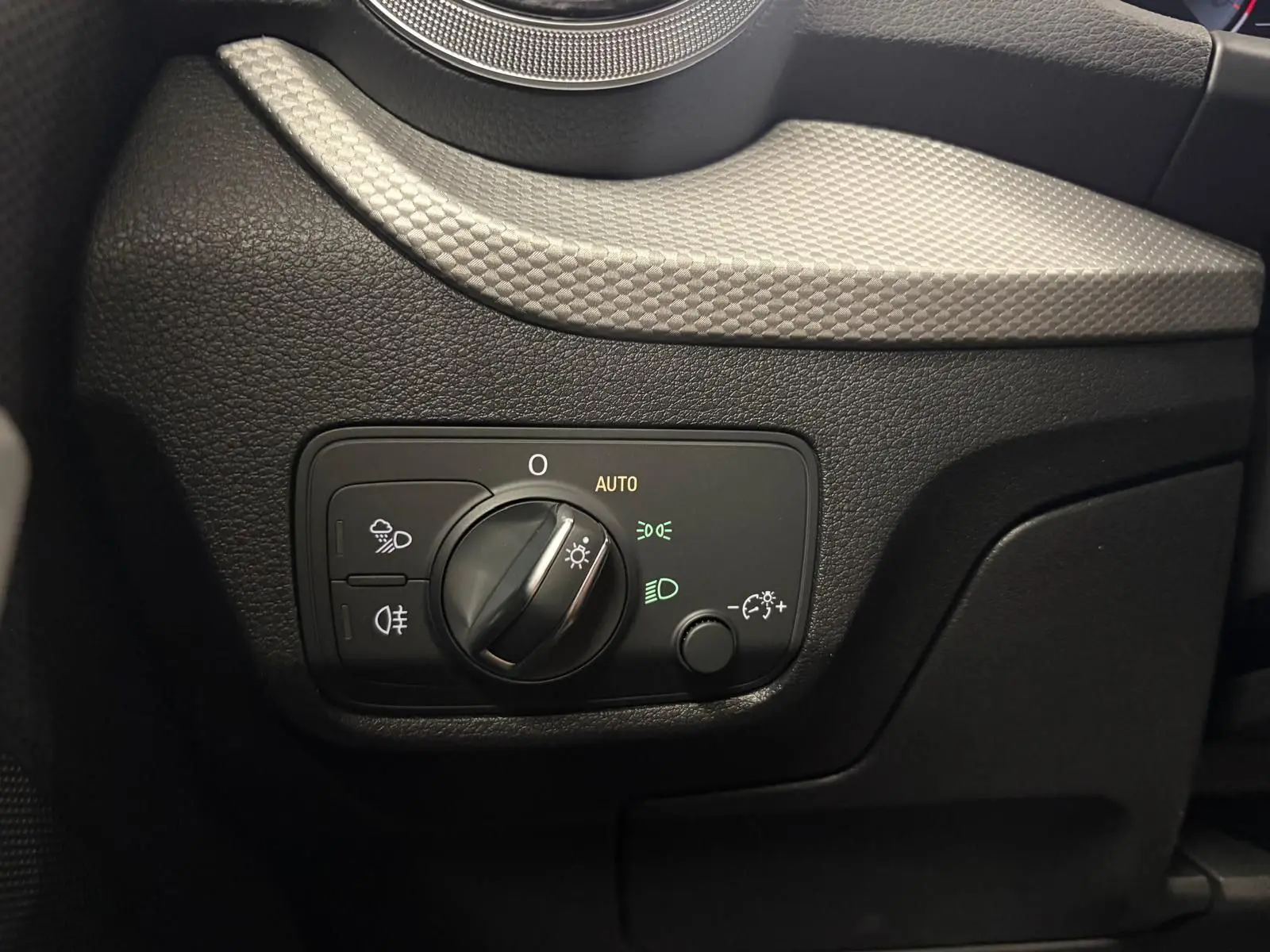 Gros plan sur le panneau de commande des phares à gauche du volant dans l’Audi Q2 35 TFSI S Line noir Mythic.