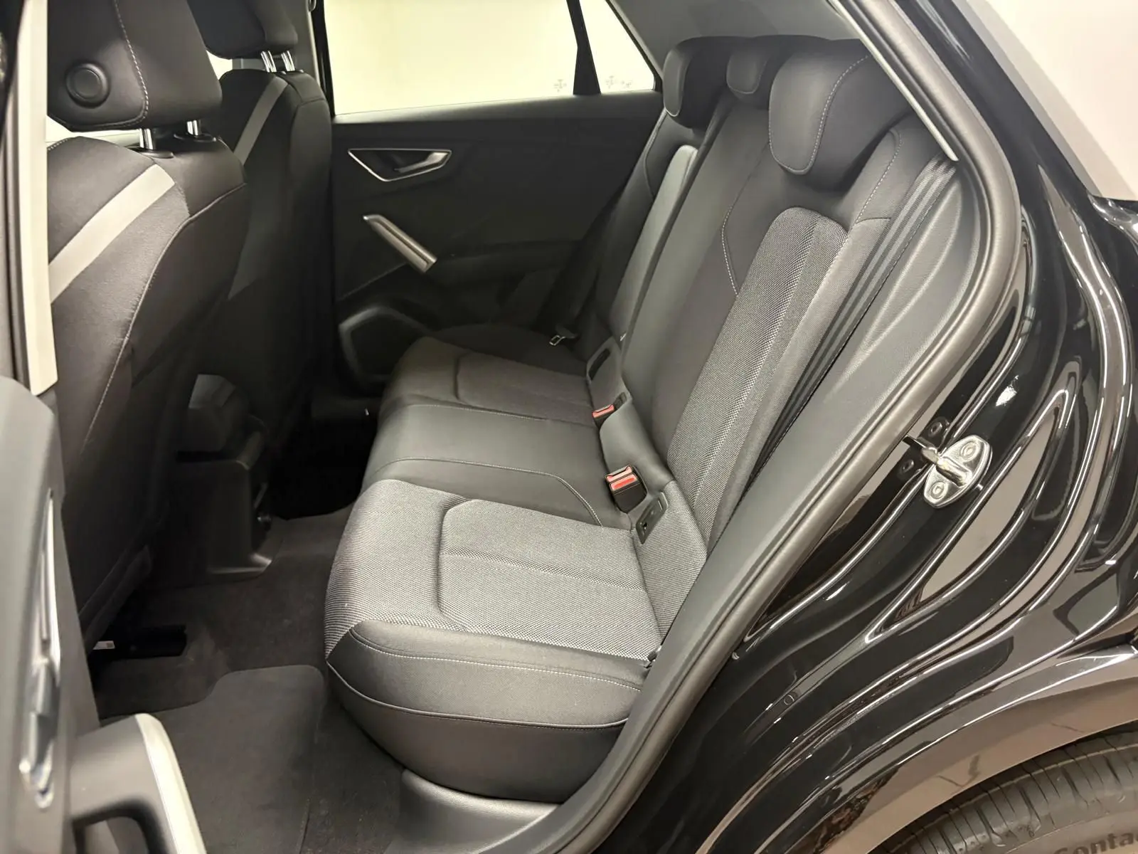 Vue intérieure côté droit des sièges arrière en tissu gris et noir d'un Audi Q2 Noir Mythic 2026, porte ouverte.
