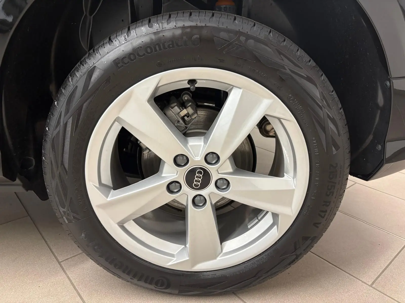 Gros plan sur la roue avant gauche de l’Audi Q2 35 TFSI 150 S Line noire avec jante argentée cinq branches.