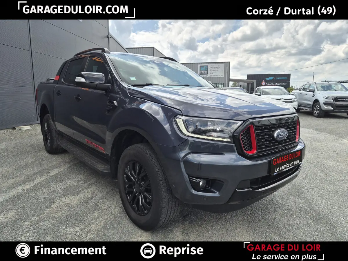 Vue 3/4 avant d'un Ford Ranger Thunder gris foncé avec calandre noire et inserts rouges, roues noires et marchepieds latéraux.
