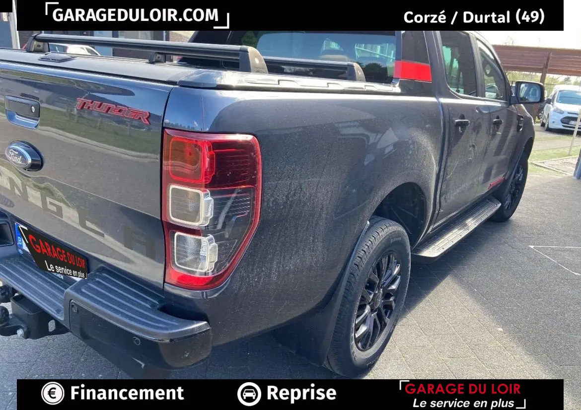 Vue 3/4 arrière droite d’un Ford Ranger Thunder gris foncé avec benne et jantes noires.
