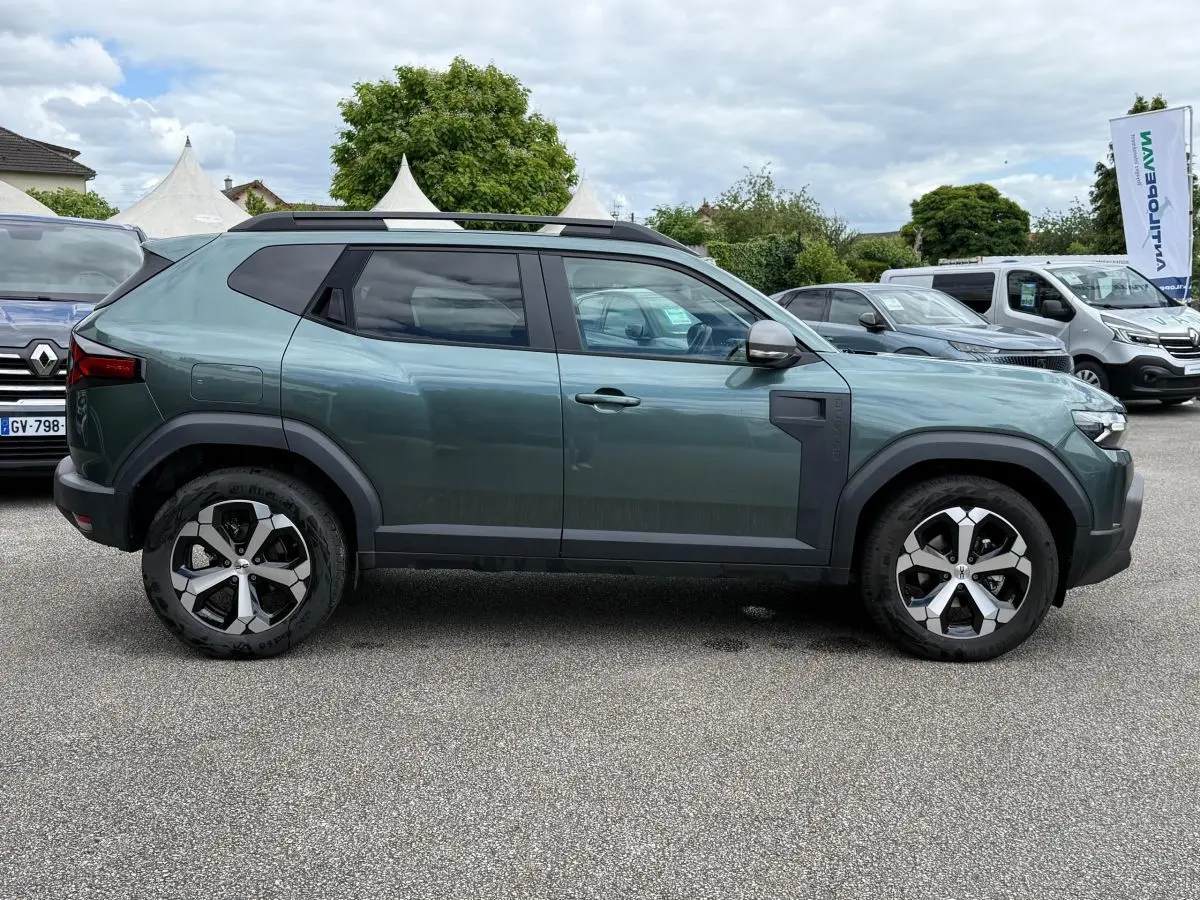 Vue de profil côté gauche d'un Dacia Duster Hybrid 140 Journey vert cèdre avec jantes alliage et barres de toit noires.