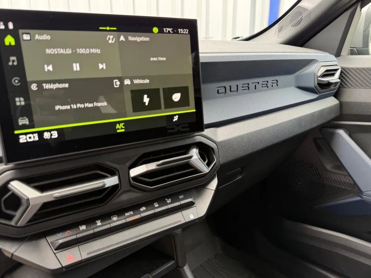 Vue intérieure côté passager du tableau de bord du Dacia Duster avec écran tactile et inscription DUSTER en relief.