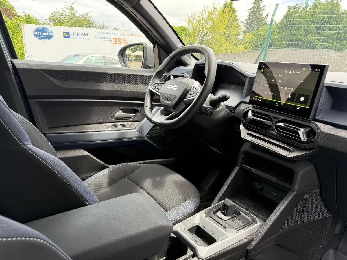 Intérieur du Dacia Duster Hybrid 140 Journey 2025 vu côté conducteur, avec écran tactile central et volant multifonctions.