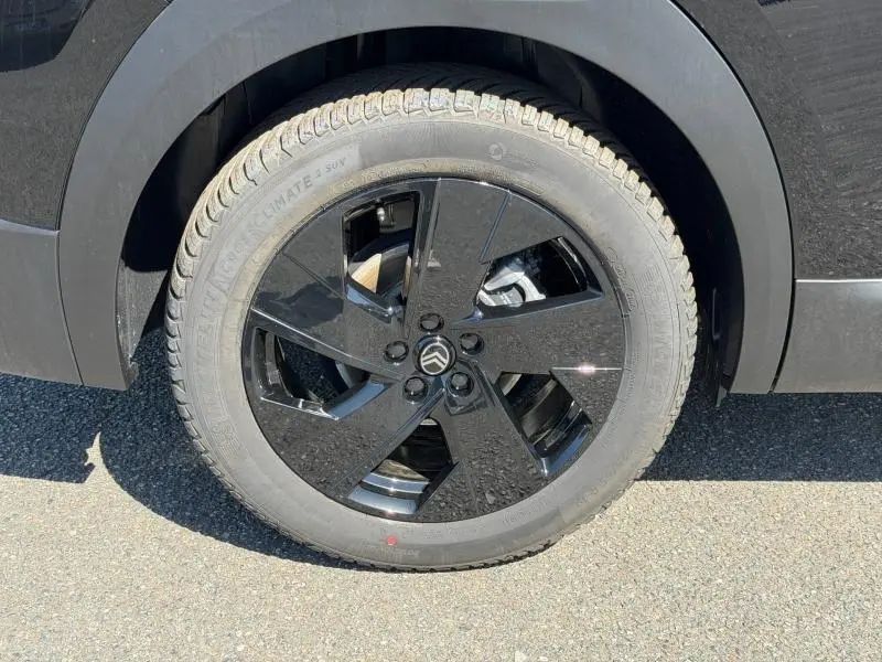 Gros plan sur la roue avant gauche noire brillante du Citroën C5 Aircross 2026 avec jante alu au design moderne.