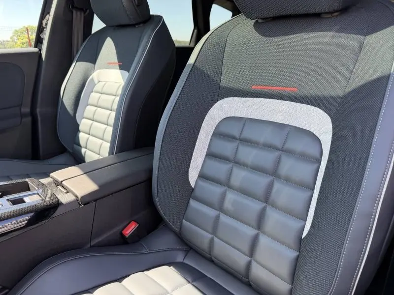 Gros plan sur les sièges avant du Citroën C5 Aircross 2026, avec sellerie noire et détails gris et rouge contrastants.