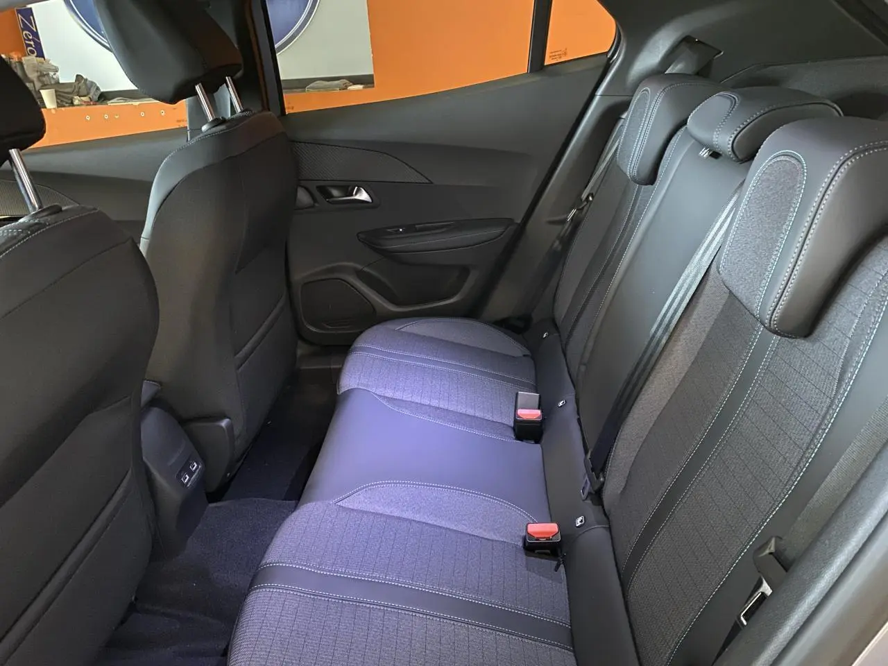 Vue intérieure arrière du Peugeot 2008 e-136 Allure Pack 2022, sièges gris noir en tissu et cuir avec surpiqûres bleues.
