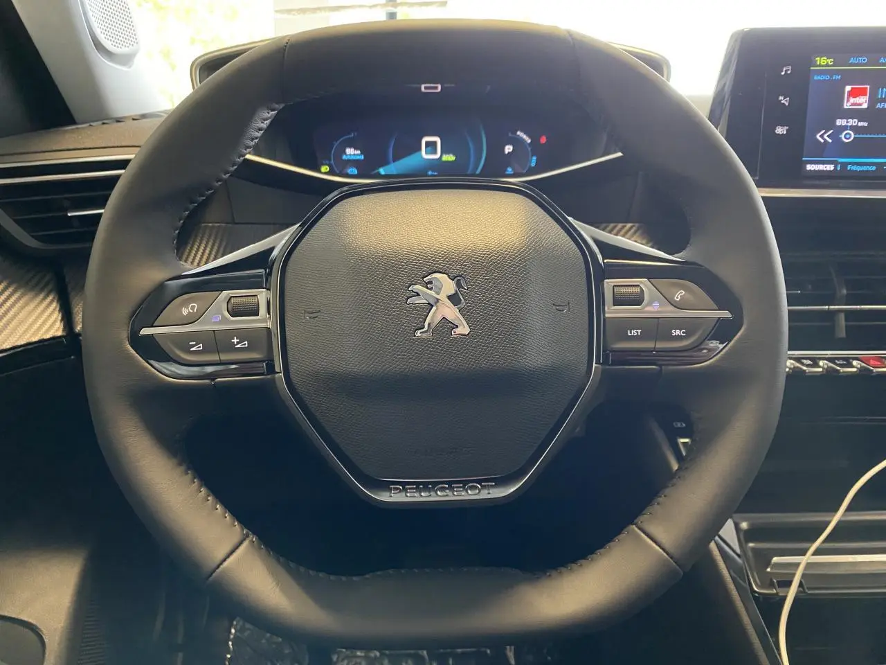Vue rapprochée du volant cuir noir du Peugeot 2008 e-136 Allure Pack avec tableau de bord numérique et écran tactile.