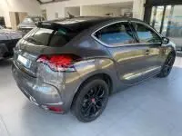 Vue 3/4 arrière droite d'une DS4 gris Platinium de 2017 avec feux LED et jantes noires en intérieur showroom.