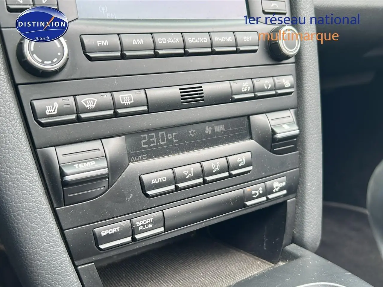 Détail de la console centrale noire d'une Porsche Boxster 987 avec commandes climatisation et audio visibles.
