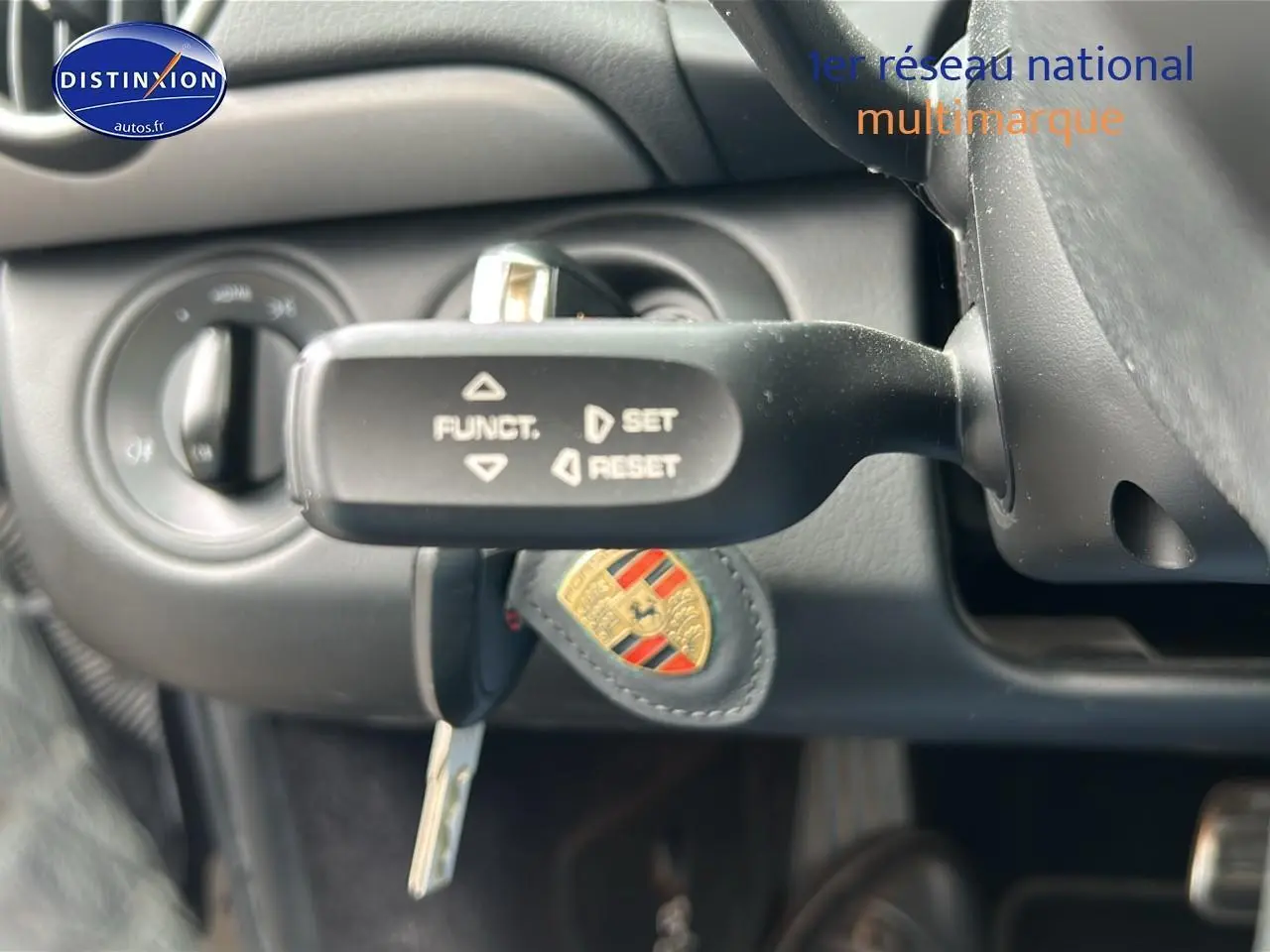 Gros plan sur la commande de régulateur de vitesse et la clé Porsche dans l'habitacle noir d'une Boxster 987.