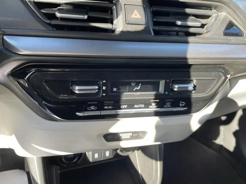 Vue rapprochée de la console centrale de la Suzuki Swift blanche 2025, montrant les commandes de climatisation automatique.