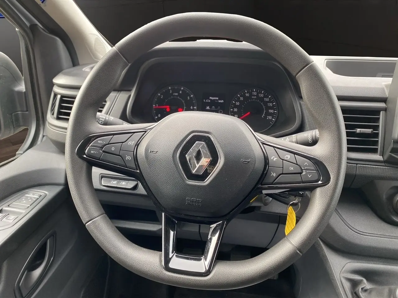 Vue intérieure centrée sur le volant noir du Renault Trafic Combi 2023 avec commandes intégrées et tableau de bord visible.