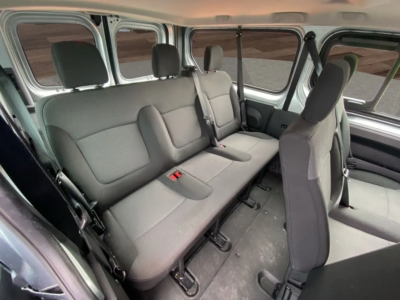 Vue intérieure latérale droite du Renault Trafic Combi gris platine 2023, montrant les sièges tissu noir pour 9 places.