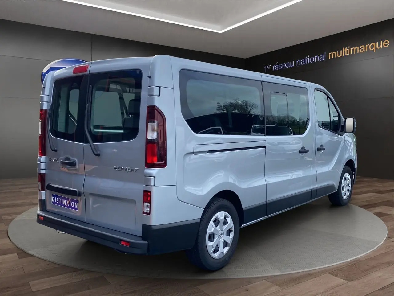 Renault Trafic Combi gris platine vu en 3/4 arrière droit, avec vitres latérales teintées et hayon double portes.