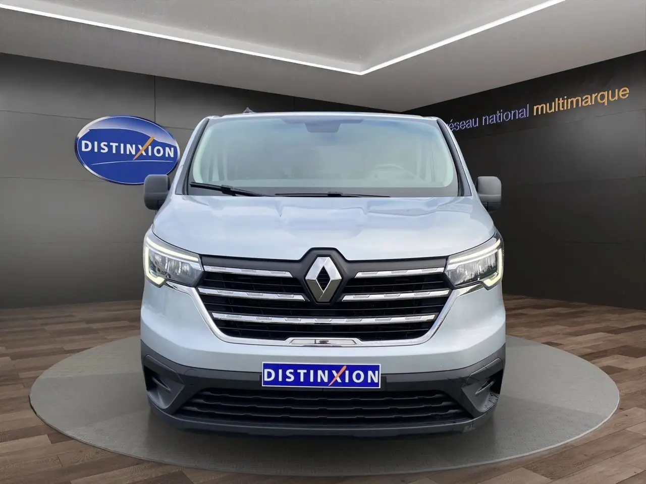 Vue frontale d'un Renault Trafic Combi gris platine 2023 avec calandre chromée et logo Renault bien visible.