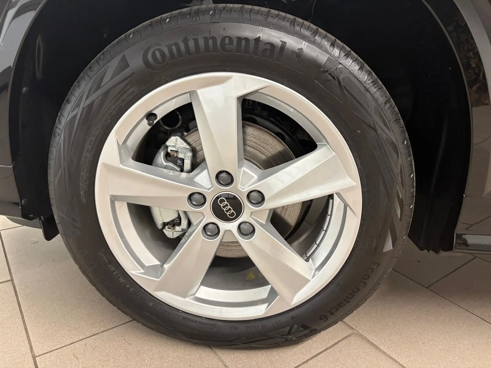 Gros plan sur la roue avant gauche d’un Audi Q2 Noir Mythic avec jante alliage argentée et pneu Continental.