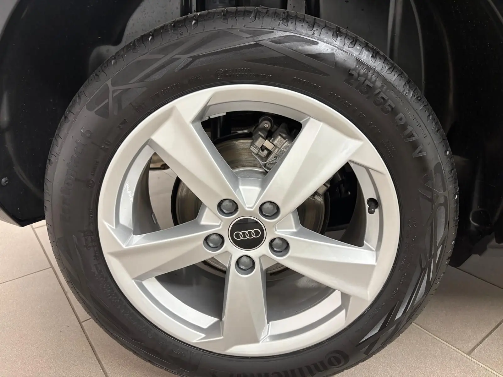 Gros plan sur la roue avant droite de l'Audi Q2 35 TFSI 150 S Line 2026 en Noir Mythic avec jante alliage cinq branches.