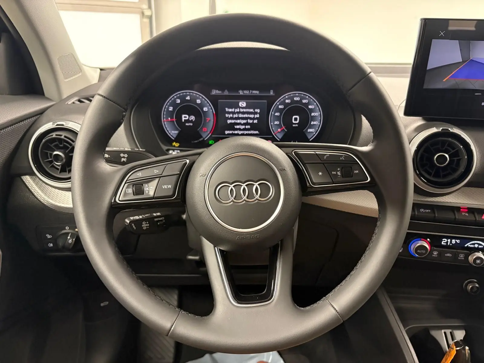 Vue centrée sur le volant multifonction de l'Audi Q2 35 TFSI S Line 2026 avec tableau de bord digital et aérateurs ronds.