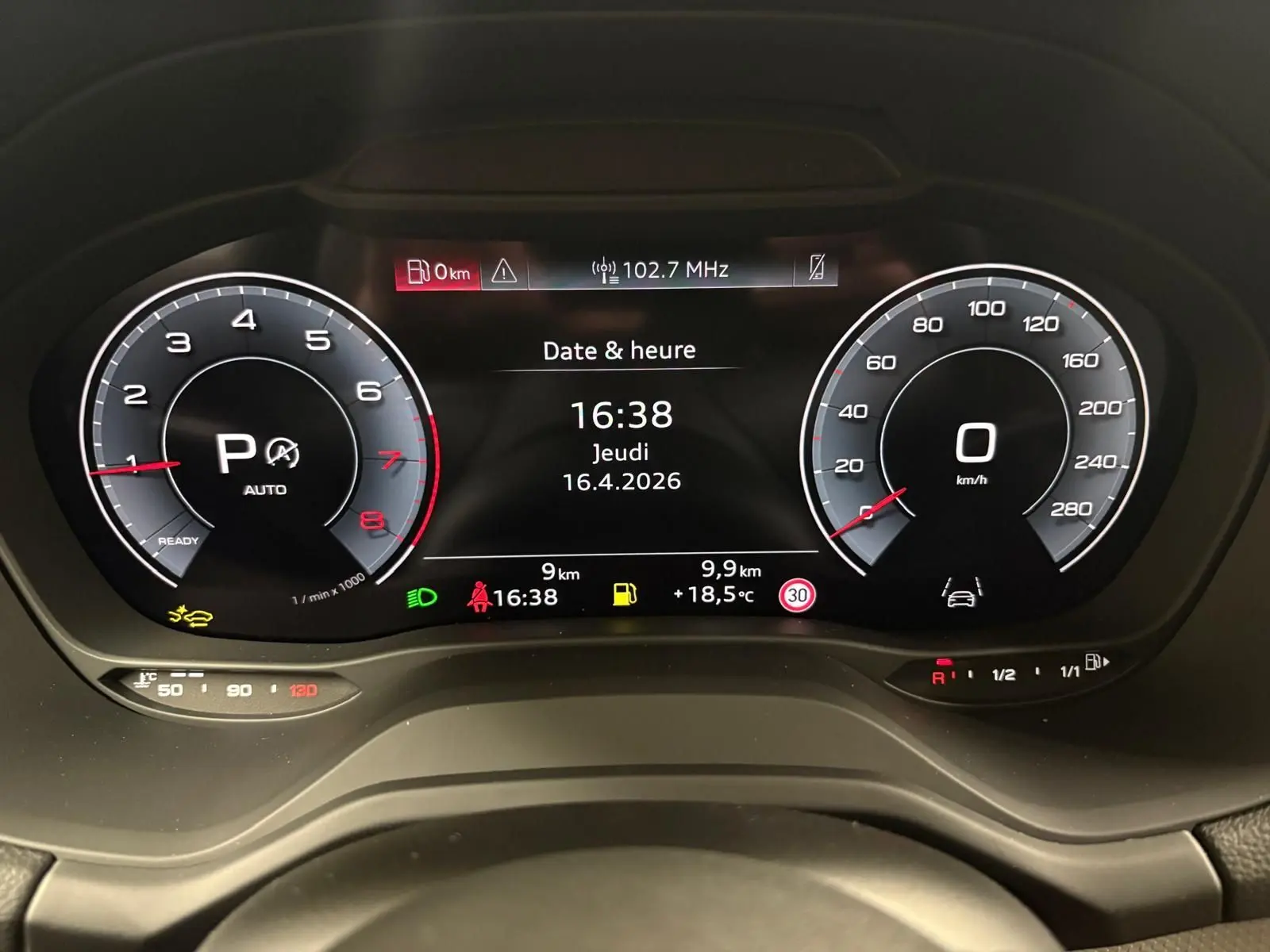 Vue rapprochée du tableau de bord numérique de l'Audi Q2 35 TFSI 2026 affichant la date, l'heure et les compteurs en mode parking.